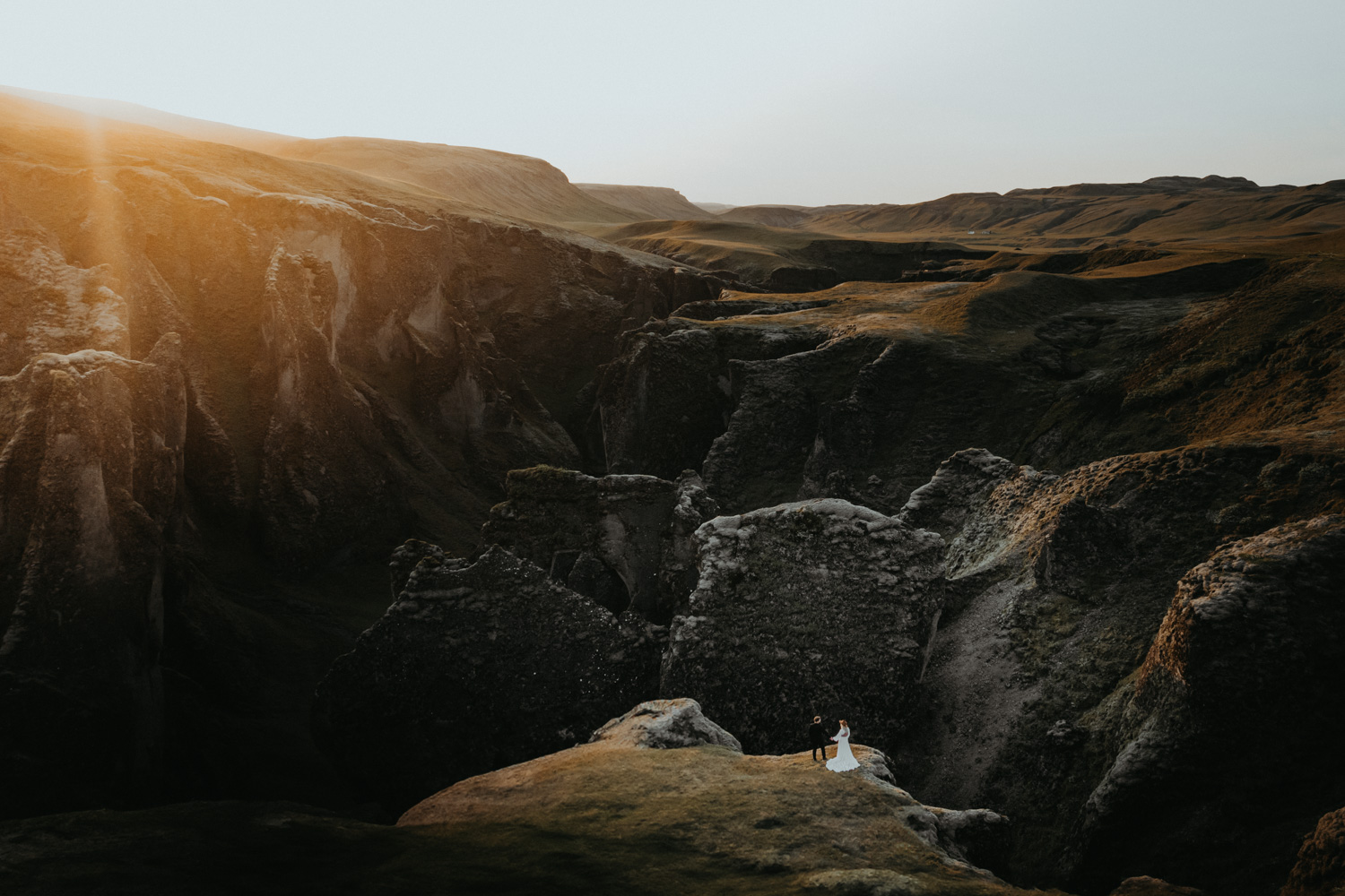 Chelsi and Josh renewing their vows above an Icelandic canyon in golden evening light