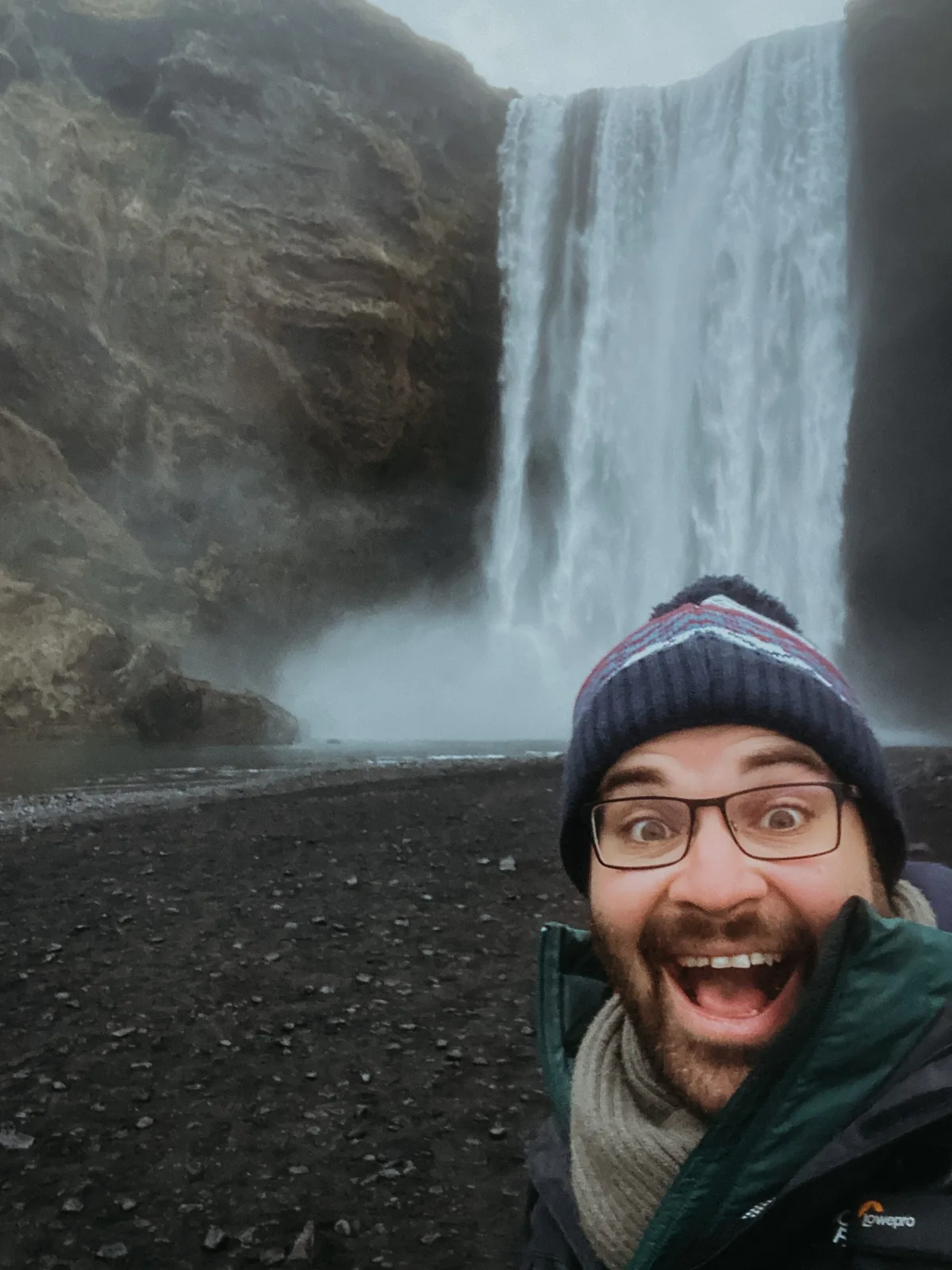 Tez smiling beside Skógafoss waterfall